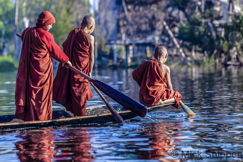 Young Buddhist monks collecting alms at a stilted village on Inle Lake.