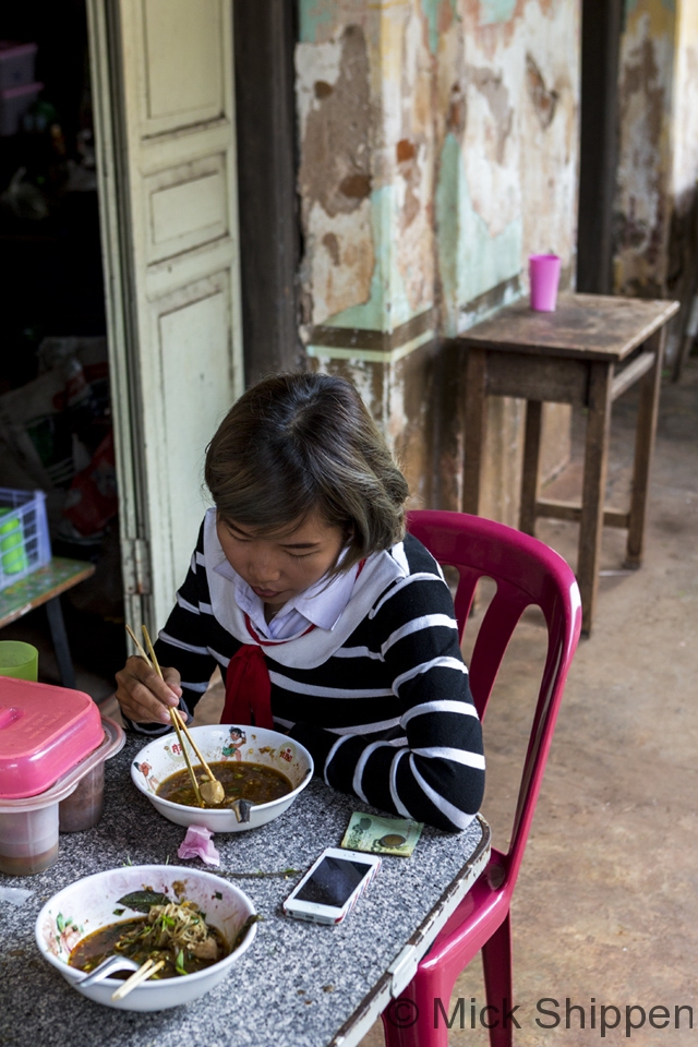 Eating noodles outside an old shophouse, Nakhom Phanom, Thailand