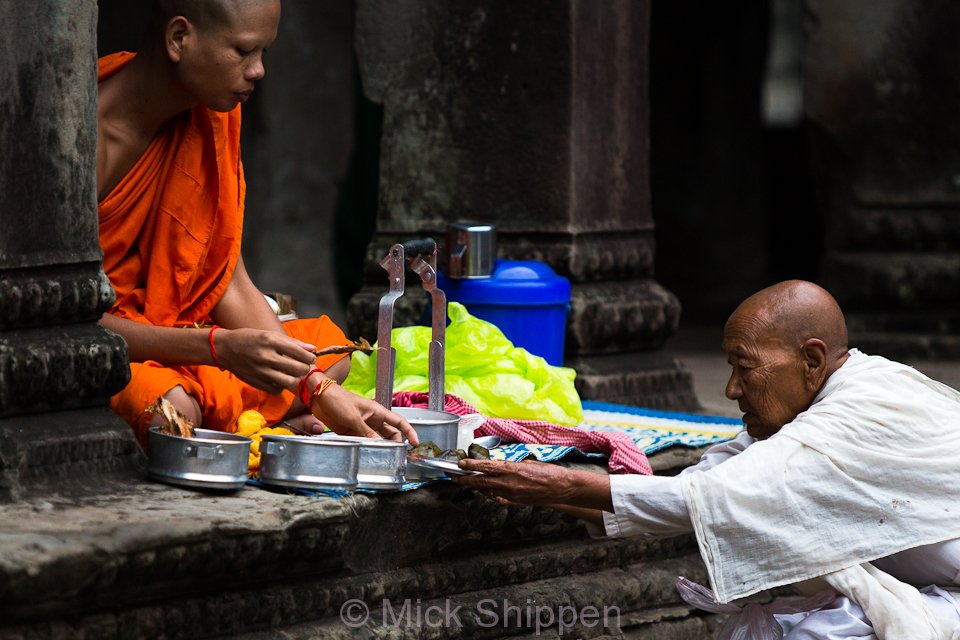 Buddhist nun making an offering to a monk at Angkor Wat, Siem Reap, Cambodia.