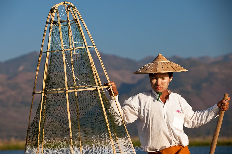 A fisherman on the lake using the distinctive traditional fishing baskets and net.